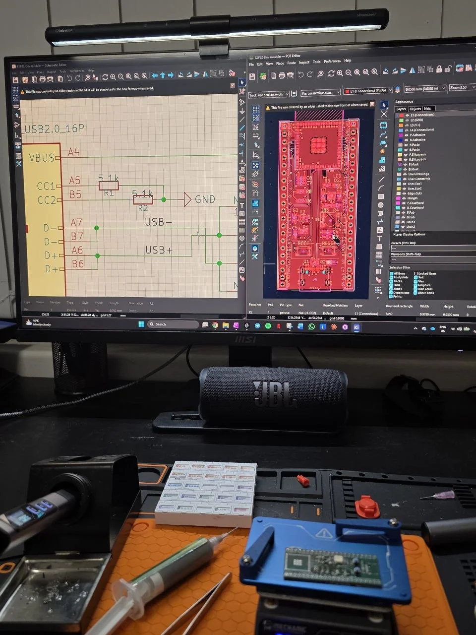Soldering bench with the board on the hotplate and the KiCad design on screen
